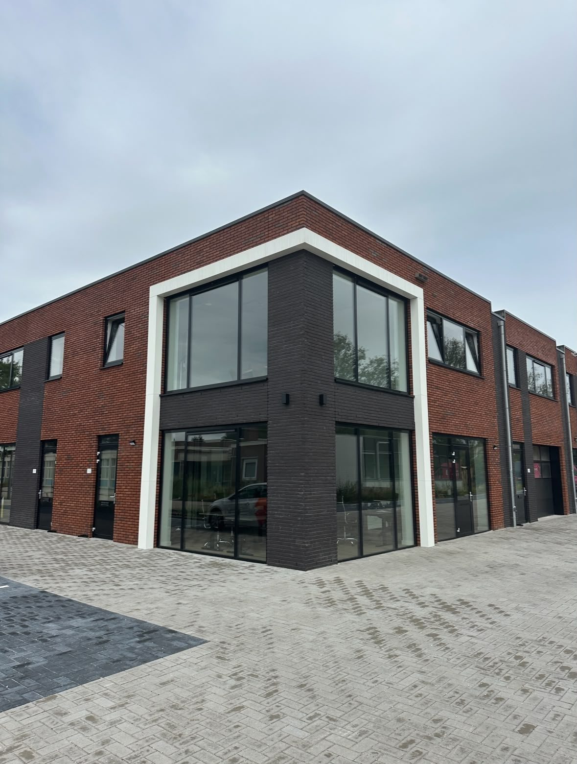 Hoek van het verzamelpand Jagtlustweg 3 met rode baksteen, donkere accenten en grote glaspartijen